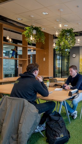 Studenten met laptops werken samen aan tafels 