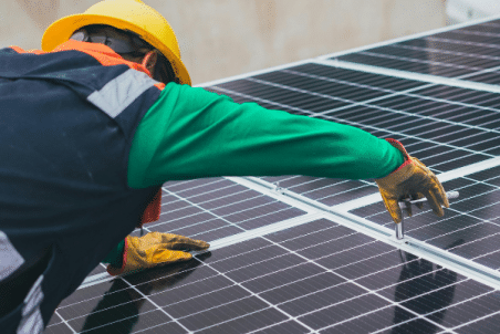 Een man installeert zonnepanelen op een dak