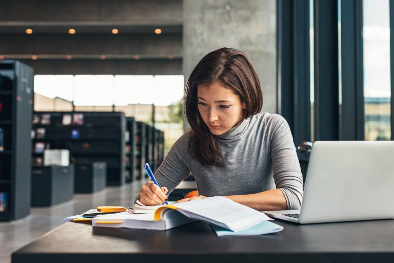 Vrouw studeert met laptop in bibliotheek