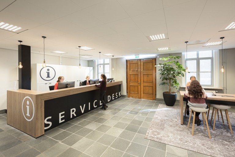Een vrouw vraagt iets bij een servicedesk