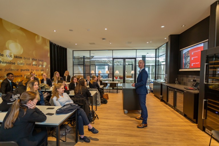 Een docent staat voor een lokaal met studenten