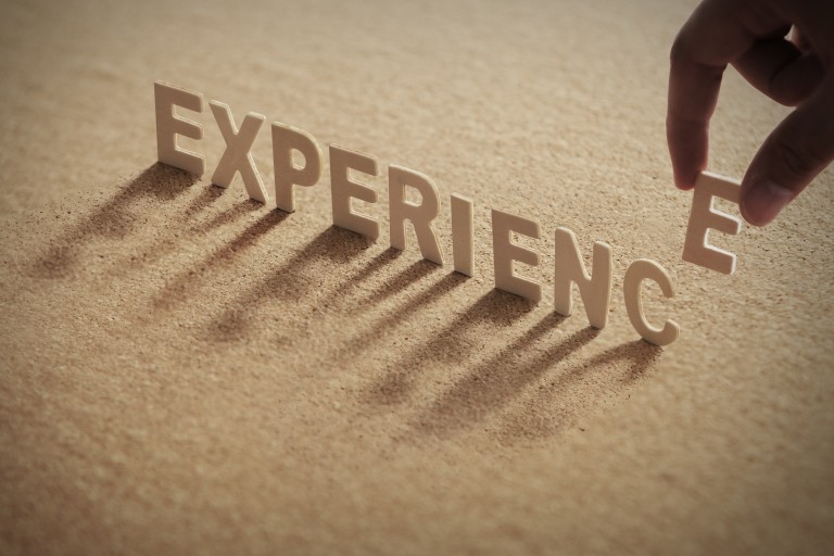 De letters van het woord Experience staan in het zand