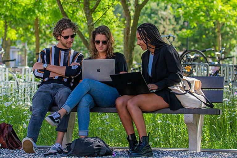 Drie studenten werken op een bankje op de BUas campus