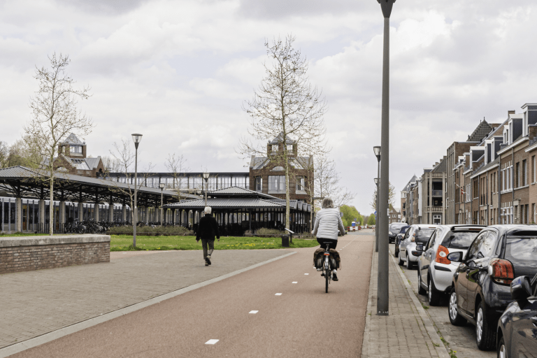 Mensen fietsen en wandelen langs geparkeerde auto's