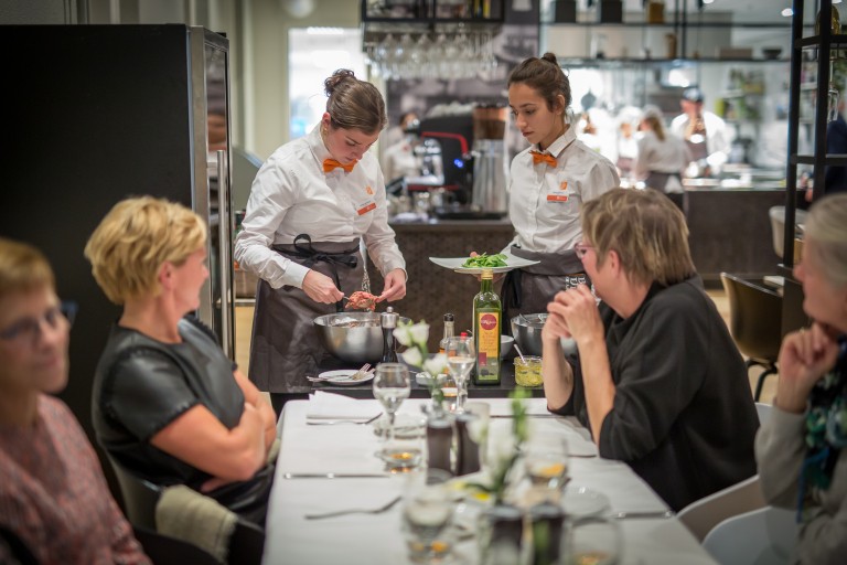Twee studenten dienen een bord op in een restaurant