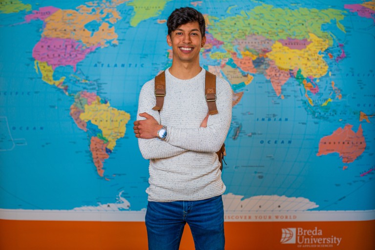 Een student staat voor een wereldkaart