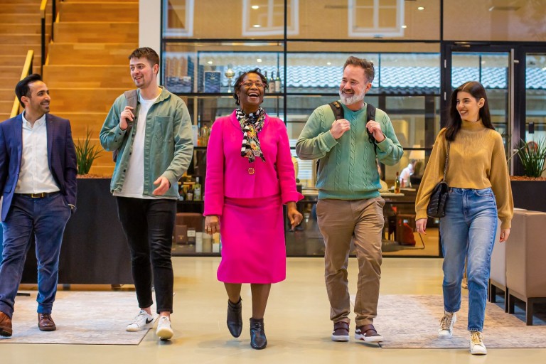Groep studenten en docenten lachend op een rij
