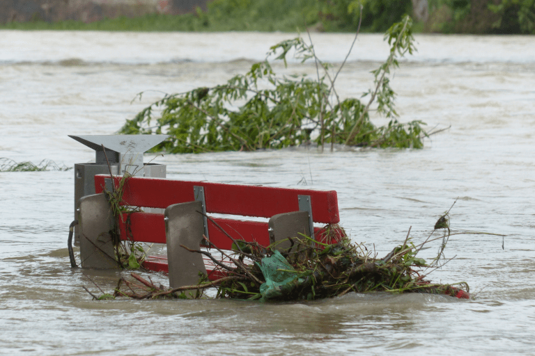 Een bankje staat bijna onder water tijdens een overstroming