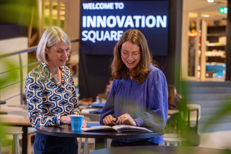 Een student en een vrouw bekijken samen een brochure