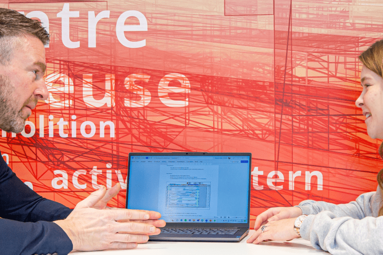 Een docent en student praten over iets op een laptop