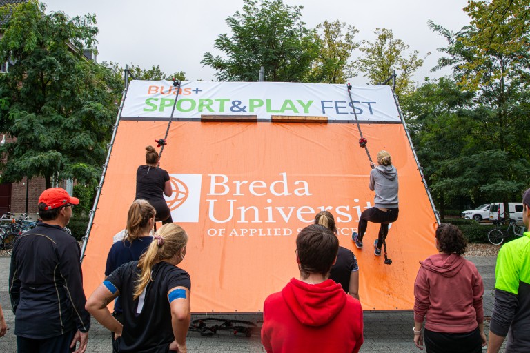 Twee studenten beklimmen een touw aan een muur