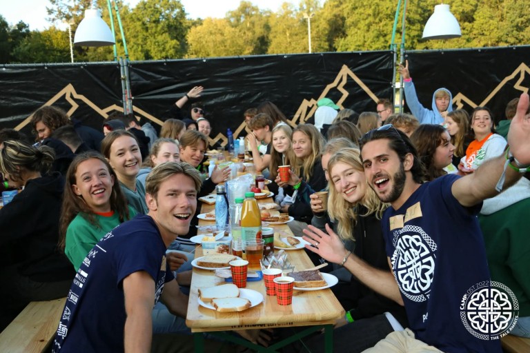 Lachende studenten eten samen aan lange tafels