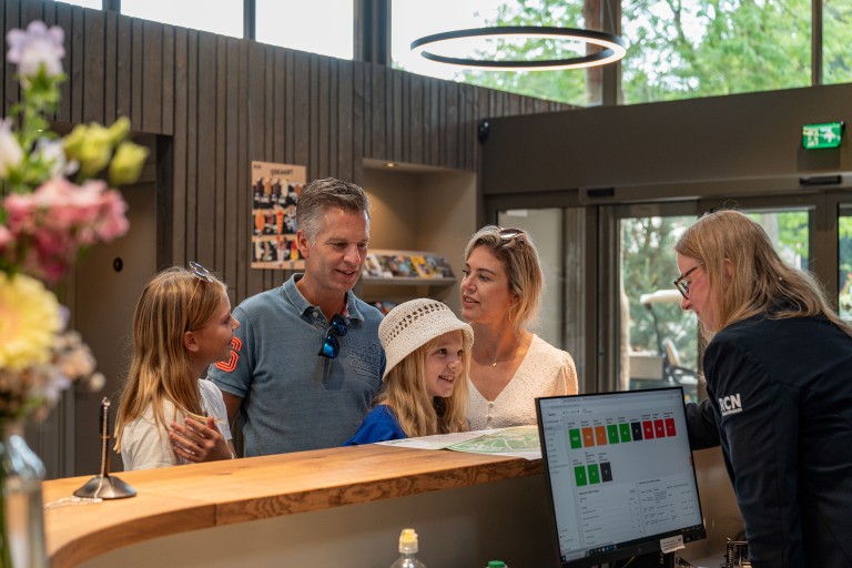 Een gezin praat met een vrouw achter een servicebalie