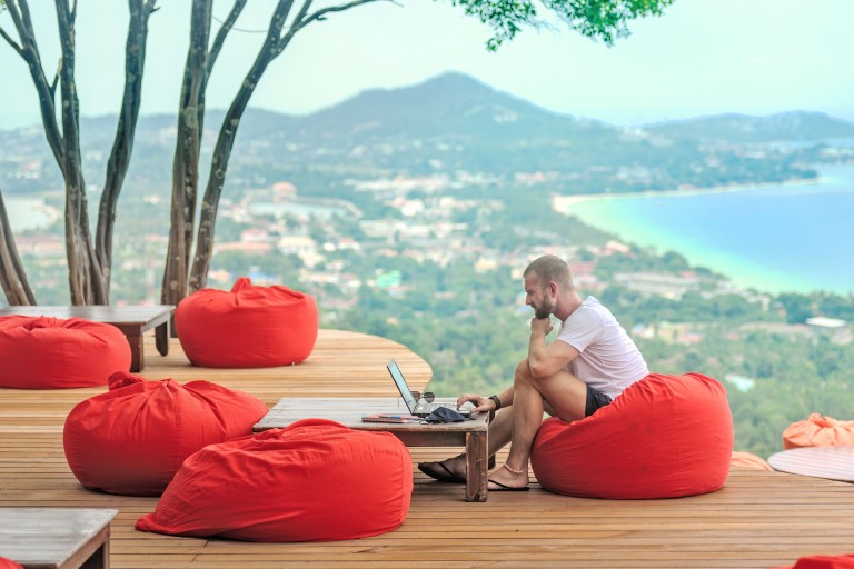 A man working on a laptop on a sunny terrace