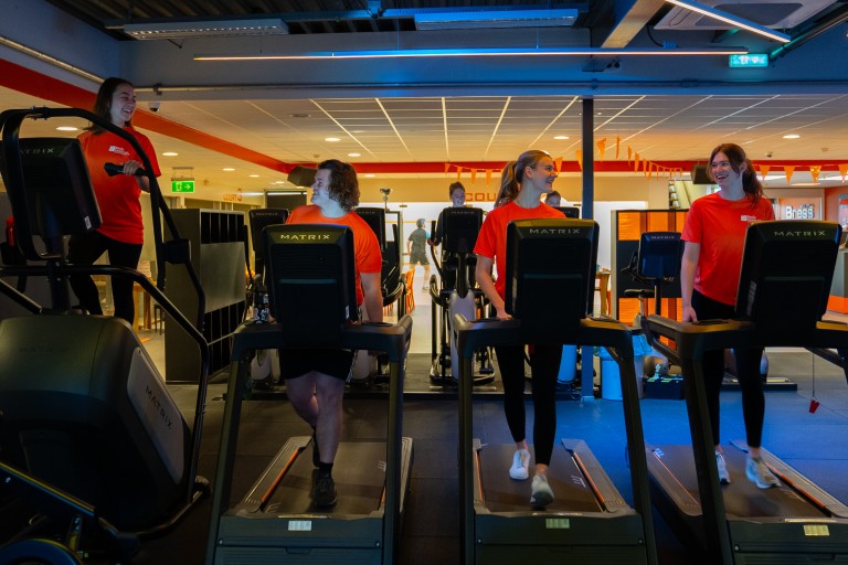 Vier studenten sporten op een loopband in een sportschool