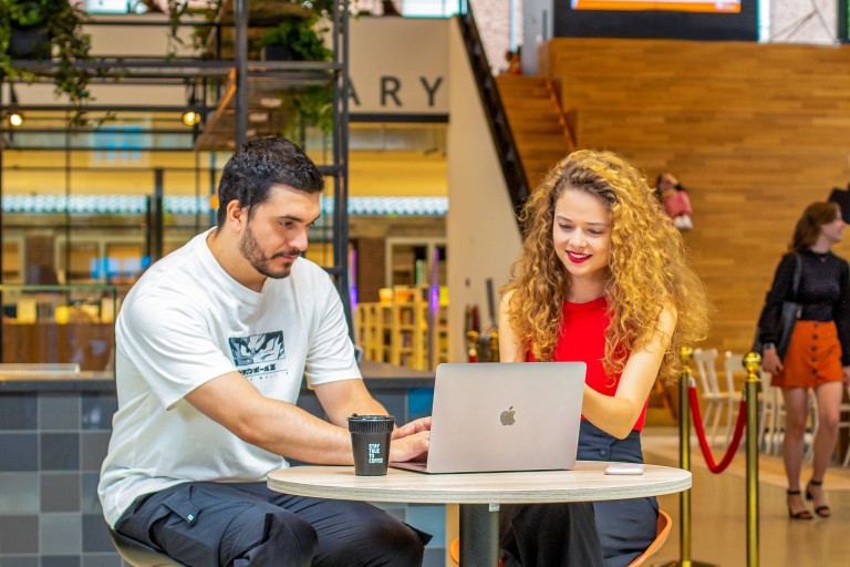Twee studenten kijken samen op een laptop