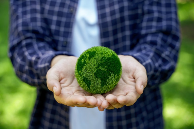 Een man houdt een wereldbol van gras vast