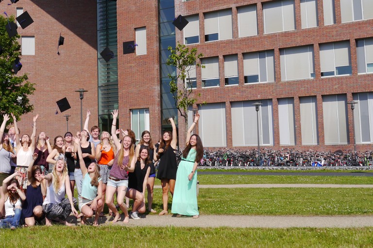 Afgestudeerde studenten gooien hun afstudeerhoed in de lucht