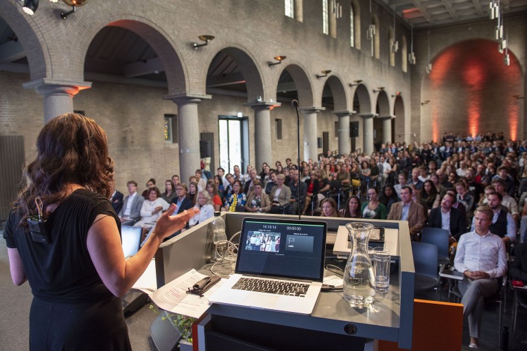 Een vrouw geeft een presentatie voor een grote zaal