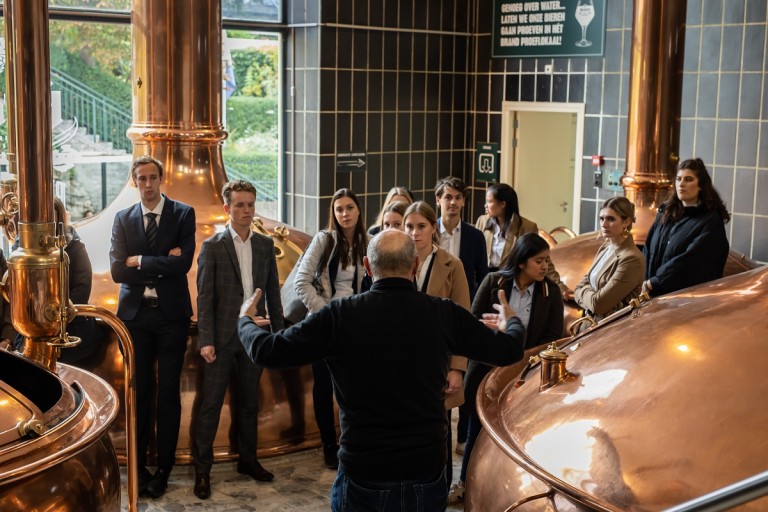 Studenten luisteren naar een uitleg in een brouwerij