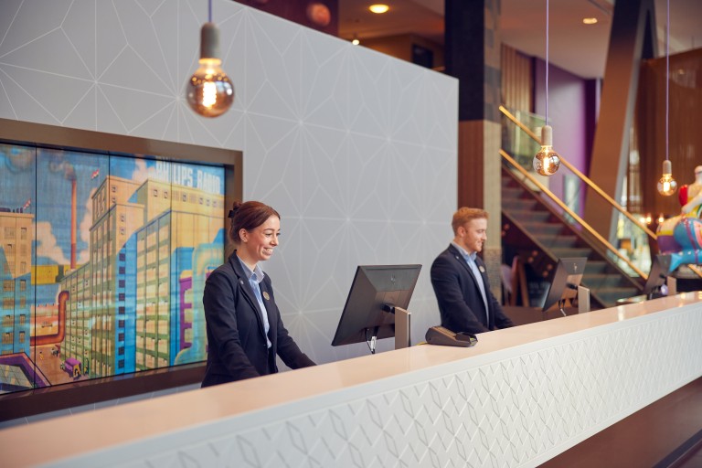 Twee mensen staan achter een receptiebalie 
