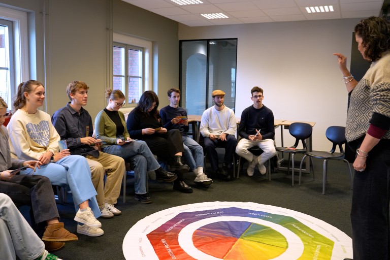 Een docent geeft uitleg aan studenten in een kring