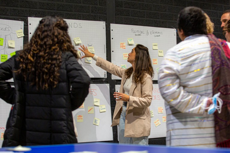 Studenten kijken naar een docent bij een bord met post-its