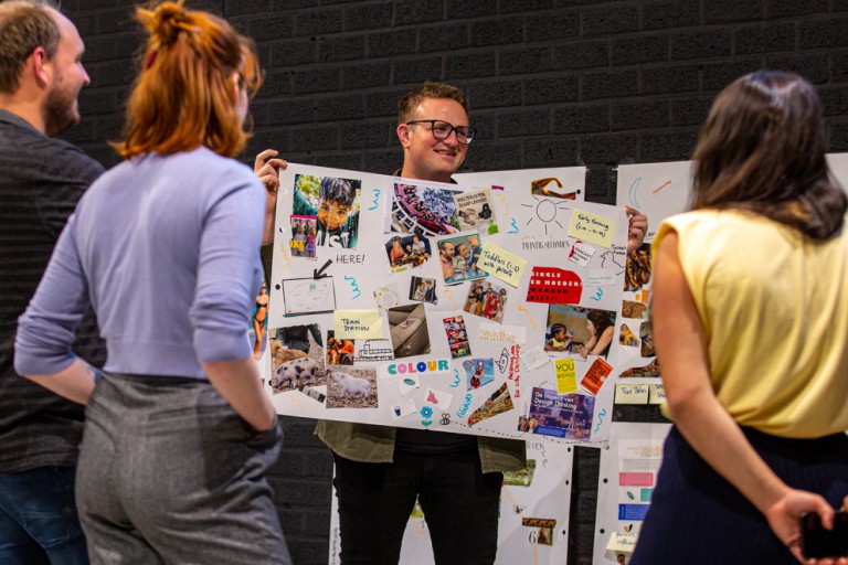 Een student laat zijn collage aan anderen zien