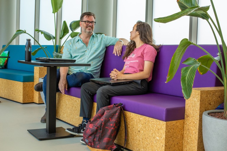 Een docent en student zitten op een bank 