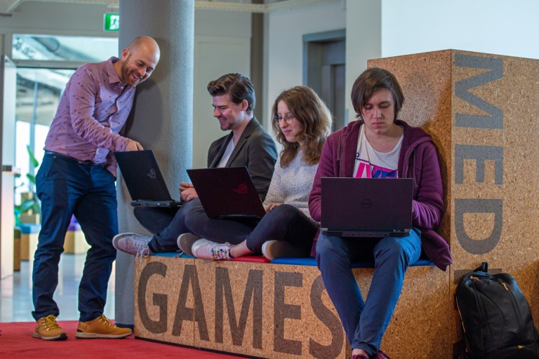 Een docent staat bij werkende studenten op een laptop