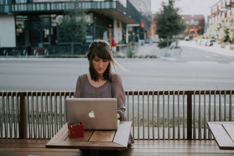 Een vrouw werkt op een laptop op een terras