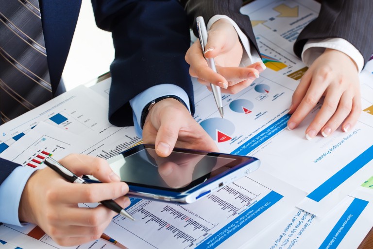 Twee mensen werken met een tablet en papieren met grafieken