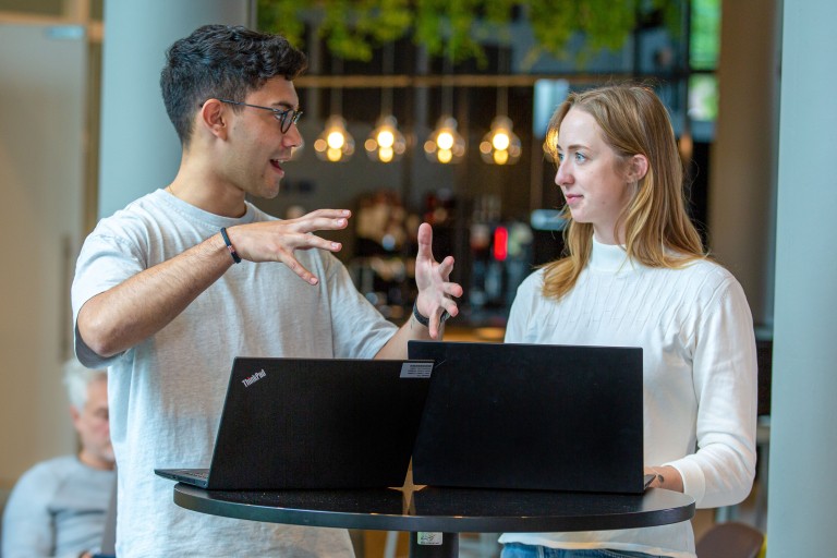 Een student legt iets uit aan een andere student
