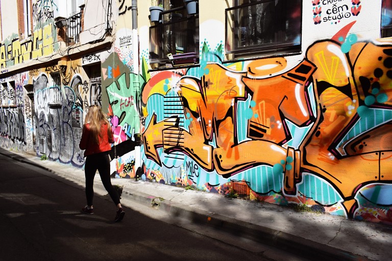 Een vrouw loopt langs een muur met graffiti
