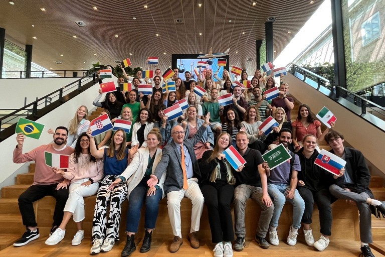 Groepsfoto van studenten die landsvlaggen vasthouden