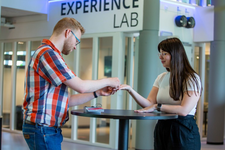 Een man helpt een student aan een statafel