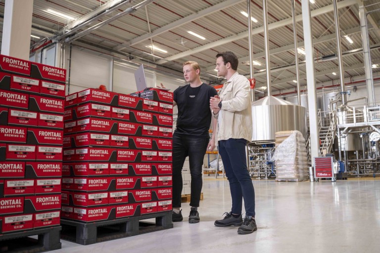 Twee mannen in een fabriek werken op een laptop