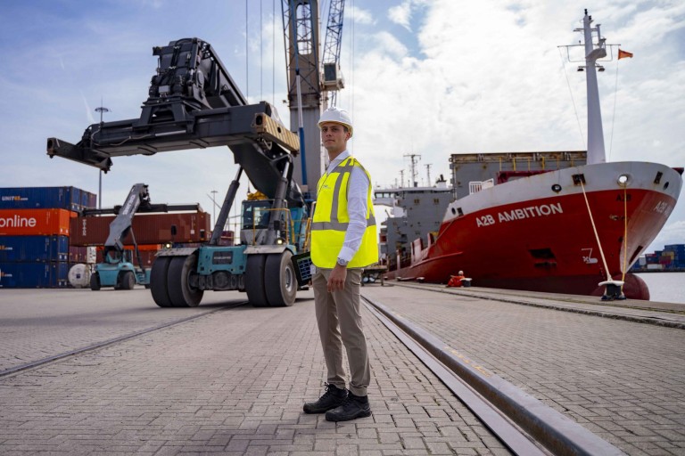 Een man staat bij een containerschip in een haven