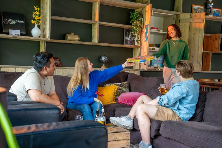 Vier studenten pakken een spel uit een kast