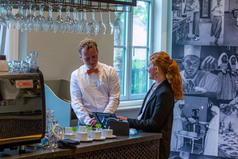 Twee studenten werken bij de bar van een restaurant