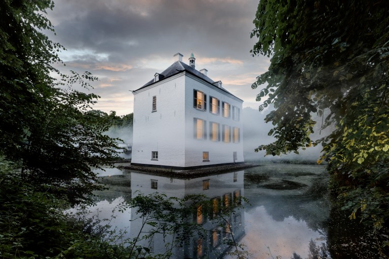 Een wit huis staat in het midden van een meer in een bos