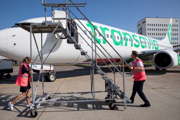 Twee mensen rollen een trap naar een vliegtuig