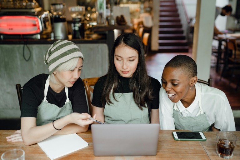 Die vrouwen met een schort werken samen op een laptop