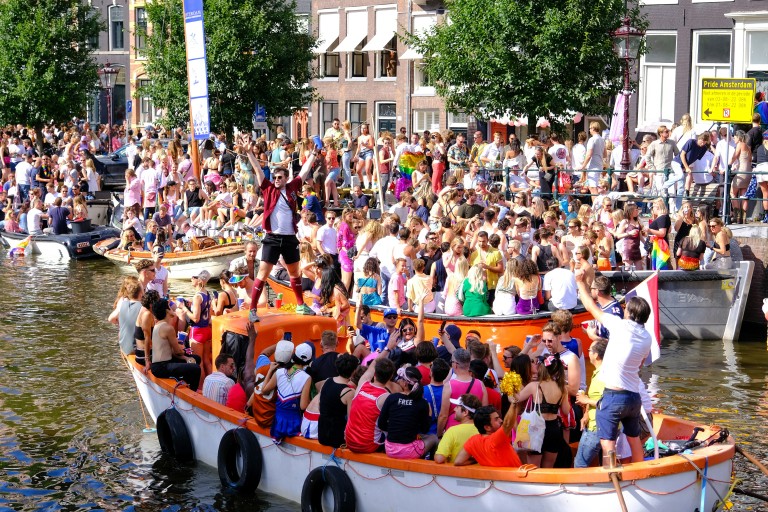 Dansende mensen op boten in de grachten tijdens Pride