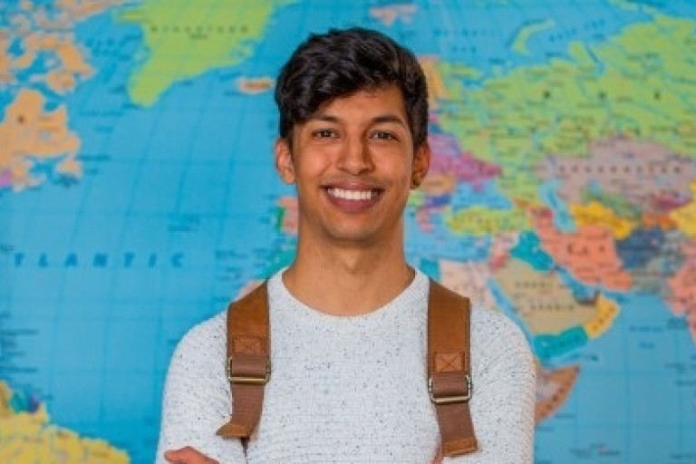 Een student staat voor een wereldkaart