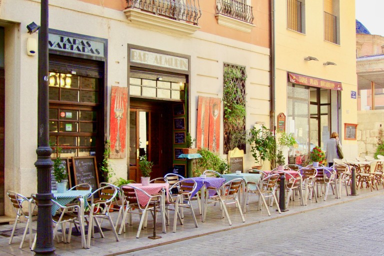 Stoelen en tafels van een Spaans restaurant staan op de stoep 