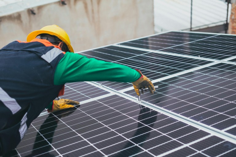 Een man installeert zonnepanelen op een dak