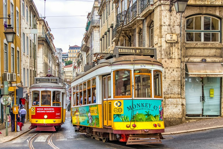 Twee oude gele trams rijden door Lissabon
