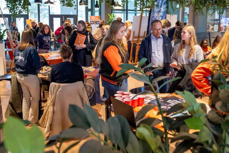 Studenten en docenten praten met bezoekers op de open dag 