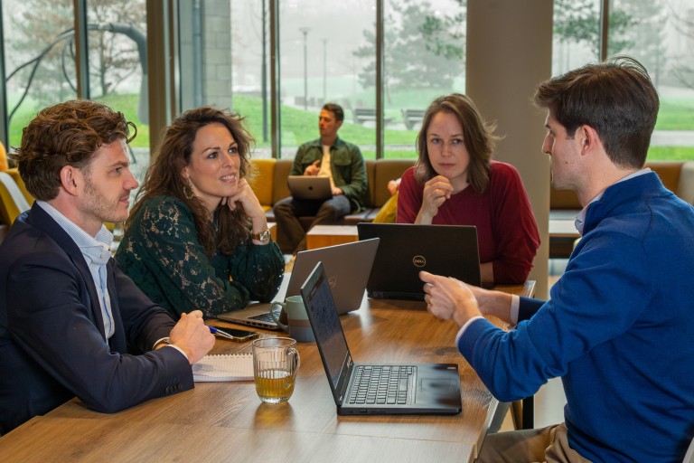 Vier mensen overleggen aan een tafel